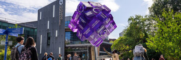 Students next to Sheffield Students' Union and looking at a purple cube