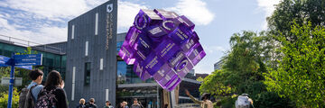 Students next to Sheffield Students' Union and looking at a purple cube