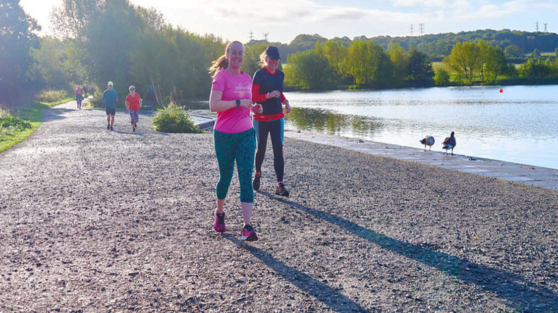 Runner on path by lake in sunny weather