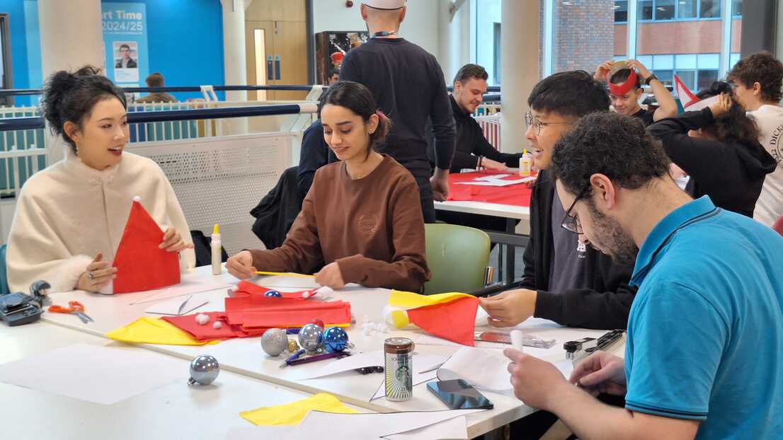 Group of students on table making paper hats