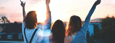 Three young women raising their hands in celebration