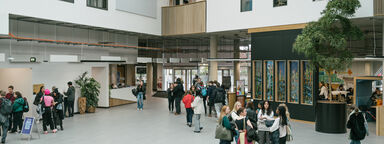 Interior shot of a large open plan building. Students walk through.
