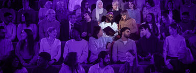 An audience in a lecture theatre with a purple filter