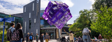 Students next to Sheffield Students' Union and looking at a purple cube