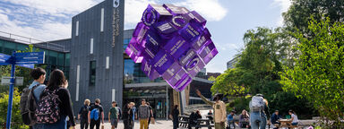 Students next to Sheffield Students' Union and looking at a purple cube