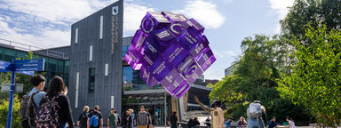 Students next to Sheffield Students' Union and looking at a purple cube