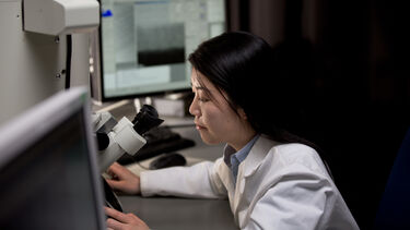 PhD researcher looking into microscope