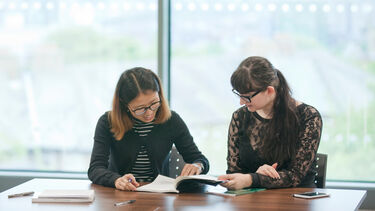 Two postgraduate students studying at a table 