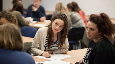 A student takes notes and listens during a group discussion