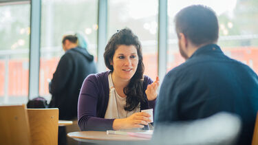 Two postgraduate students talking in cafe
