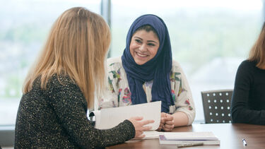 Two masters students working together with books