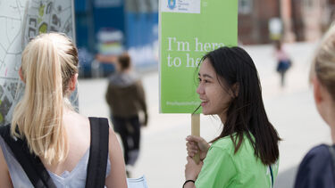 Student open day ambassador holding 'here to help' sign