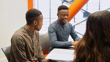 Students talking around a desk in the library