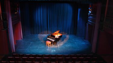 Interior of the Drama Studio with a grand piano lit by a spotlight