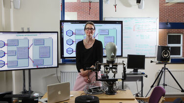 A students sits with a robot.