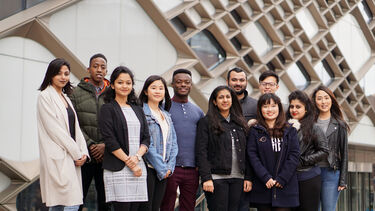 a large group of international students stand outside the Diamond building 