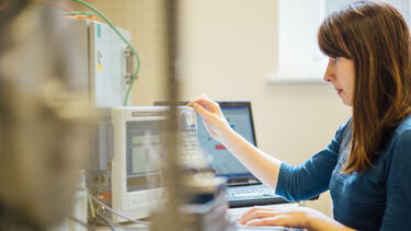 Researcher monitoring data on machines and laptop