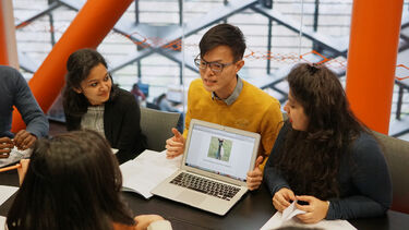 a group of students looking at a laptop in the Diamond.
