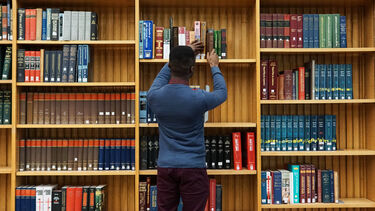 a student is taking a book off a sheld in Western Bank Library 