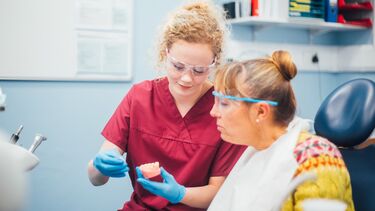 An undergraduate student shows a patient some teeth.