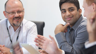 Three men discussing ideas during a meeting around a table
