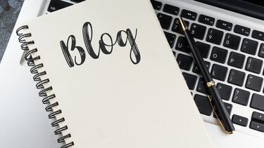 Notebook resting on laptop with "blog" written on it in calligraphy style