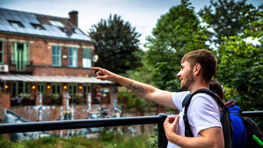 Student pointing out something by riverside