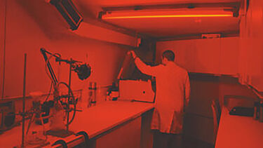 Someone at work in the  Department of Geography Home About Us Undergraduate Courses Masters Courses PhD Research Research News Facilities Luminescence dating Tanzania Field Centre Our Staff Current Students Outreach Contact us Employability Sheffield Luminescence Dating Laboratory, which is lit with a red light.