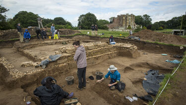A group of archaeology students at a large excavation site.
