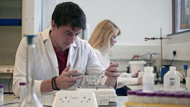 A student in a lab coat works in a Geography laboratory