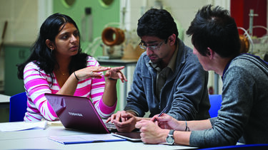 Materials Postgraduate students in discussion aroudn a laptop