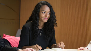 Student smiling in a seminar discussion with open books on table 