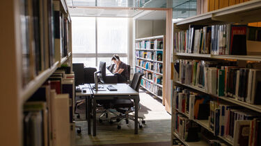 A male student studying with headphones on in the Health Sciences library. 
