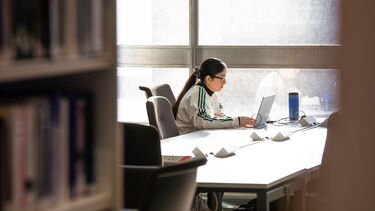 A female student using her laptop in the Health Sciences library. 