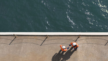 Overhead view of Caucasian technicians shaking hands near water