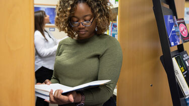 A female student reads a book in the library of the School of Health and Related Research. 