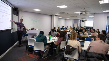 A lecture taking place in the School of Health and Related Research. The lecturer points at a presentation.