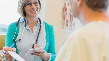 A nurse and patient. She is showing the patient a piece of paper. 