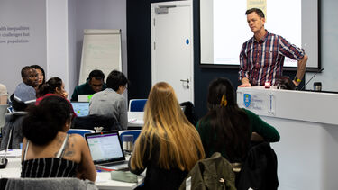 A students asks a question in a lecture and the academic listens intently to the question. 