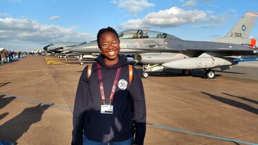 Aerospace student Favour Omolaiye standing in front of a fighter jet
