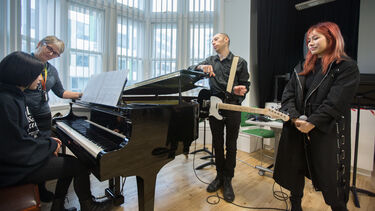 group playing instruments round a piano