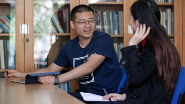 Two students sat at a desk talking.