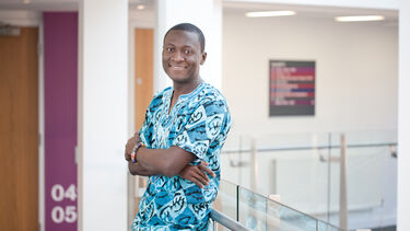 PhD student smiling at the camera on balcony