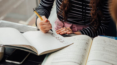 A student writing characters in a notebook