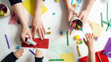 Flatlay of adult and child hands using art supplies