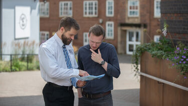 A member of security staff helping a member of the public with directions