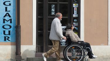 Photo of a person walking pushing someone in a wheelchair 