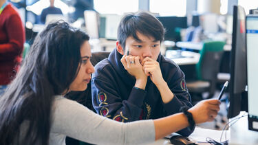 Two Information School students looking at a computer screen.