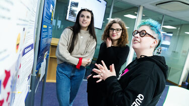 A group of students looking at a wall of information.
