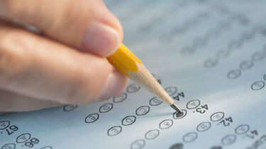 A close up of a hand marking a multi-choice question.